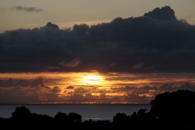 Scenic view of sea against dramatic sky during sunset