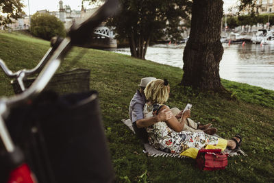 Rear view of senior couple using smart phone at lakeshore