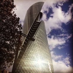 Low angle view of modern building against cloudy sky