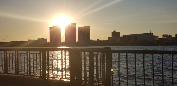 Scenic view of river by buildings against sky during sunset