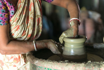 Midsection of woman making pottery