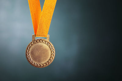 Close-up of gold medal against blackboard