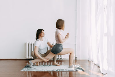 Woman and trainer in sportswear go in for yoga and fitness sports in the studio