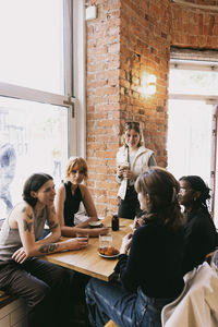 Female friends talking to each other sitting at table in cafe