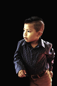 Boy in smart casual standing against black background