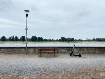 Empty benches on street against sky