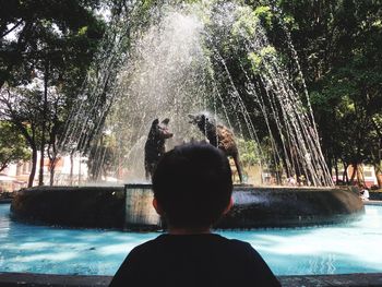 Rear view of boy looking at fountain