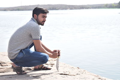 Side view of young man in squatting position at beach