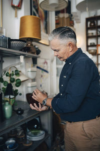 Senior male owner examining merchandise at antique store