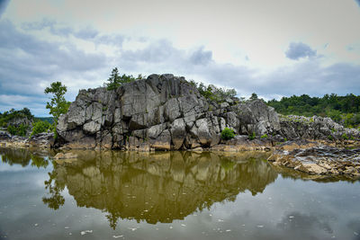 Reflection of rocks in lake against sky