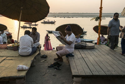 People sitting at beach against sky