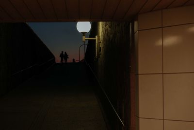 Rear view of man standing in illuminated corridor