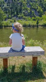 Girl sitting on bench by lake