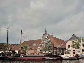 Sailboats moored in city by buildings against sky