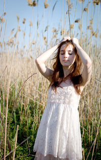 Beautiful young woman wearing hat standing on land