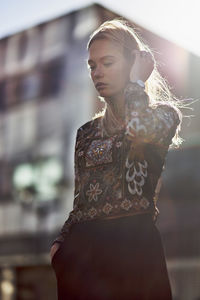 Young woman standing against buildings in city