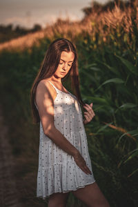 Young woman standing against plants