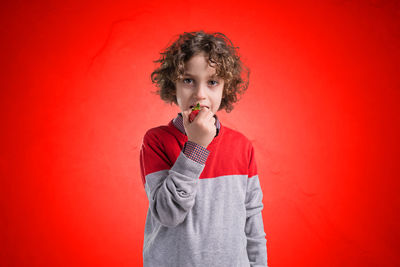 Portrait of a boy holding red over white background