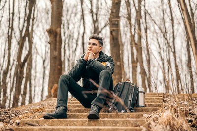 Portrait of young man sitting on tree trunk