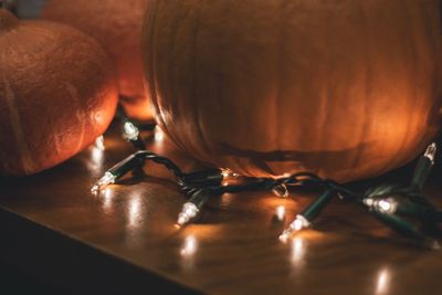 Close-up of pumpkins with illuminated string lights on table