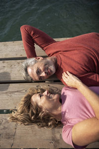 Cheerful mature woman with man lying on floorboard