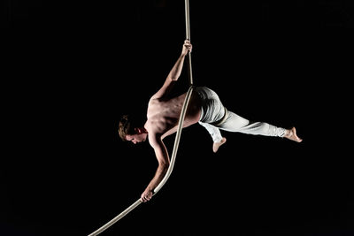 Young man doing gymnastics against black background