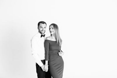 Happy elegant couple standing against white background