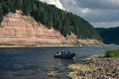 Rear view of man sitting on boat in sea against sky