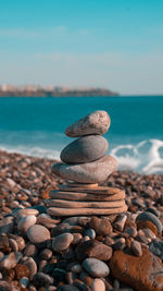 Stack of stones in sea against sky