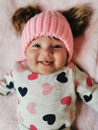 Portrait of cute baby girl laying and smiling on bed at home