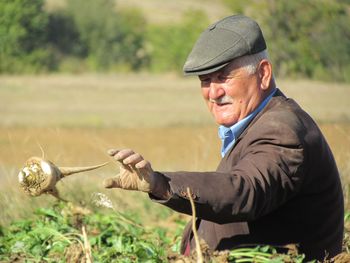 Senior man throwing vegetable at farm