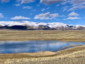 Scenic view of lake by snowcapped mountains against sky