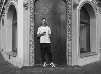 Portrait of young man standing by door of building