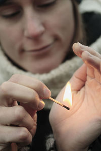 Close-up of woman's hand holding burning matchstick