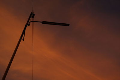 Low angle view of silhouette crane against sky during sunset