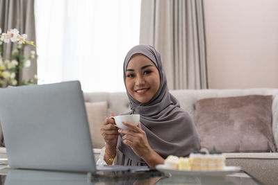 Young woman using phone while sitting at home