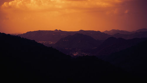 Scenic view of silhouette mountains against orange sky