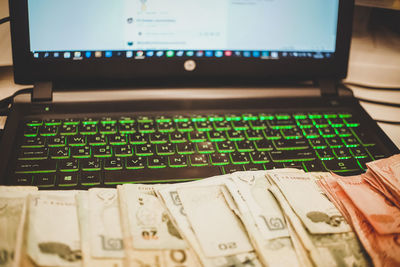 Close-up of laptop and currencies on table