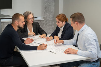 Four colleagues are discussing blueprints in a conference room in an office. brainstorming of