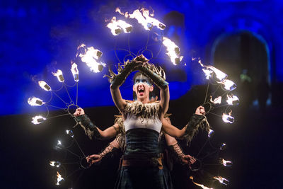 Full length of woman standing against illuminated lights at night