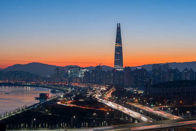 Illuminated buildings in city against sky at dusk