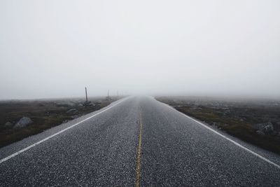 Road on snow covered landscape against sky