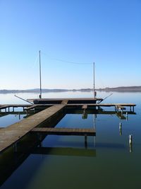 Sailboat moored on sea against clear blue sky