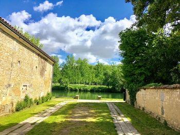 Walkway amidst trees and houses against sky