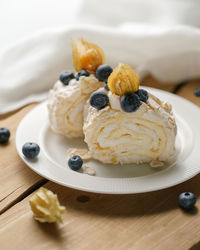 Two pieces of meringue roll with berries on a plate.