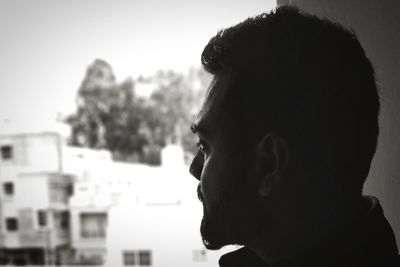 Close-up of young man looking through window