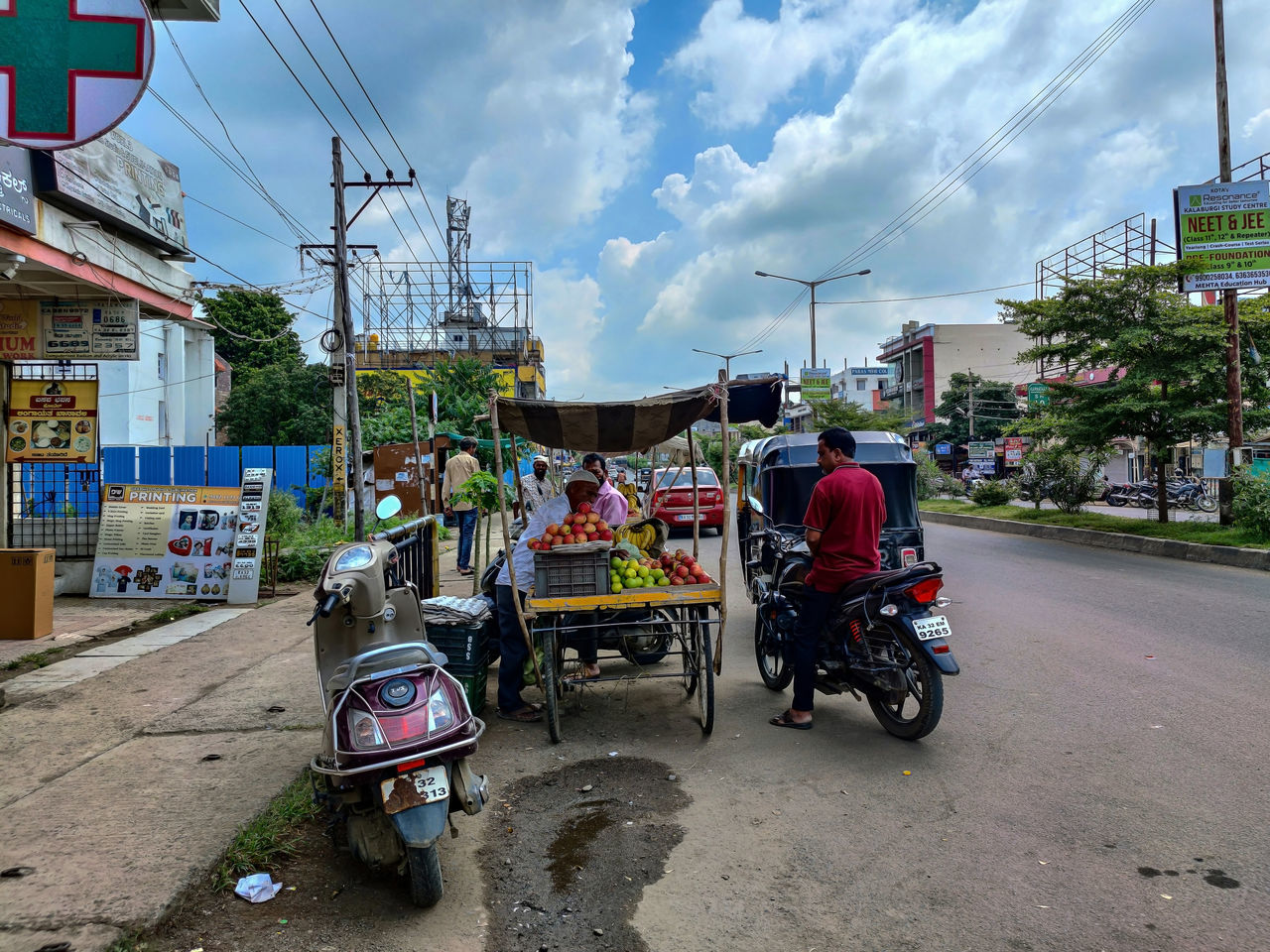 transportation, city, mode of transportation, street, architecture, rickshaw, cloud, road, sky, building exterior, motorcycle, urban area, built structure, city street, nature, travel, vehicle, city life, jinrikisha, town, land vehicle, travel destinations, traffic, outdoors, day, neighbourhood, car, building, group of people, adult, bicycle, tourism, motor vehicle, person, driving, infrastructure, transport