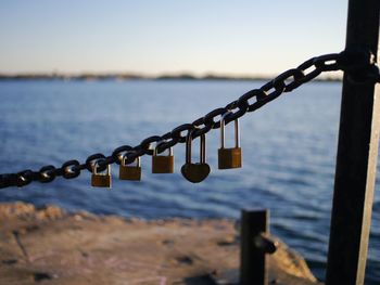 Close-up of padlocks hanging on railing next to lake