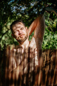 Shirtless man taking shower outdoors