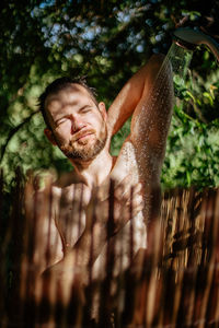 Shirtless man taking shower outdoors